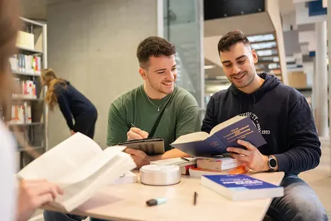 Studierende in der Bibliothek: Zum Wirtschaftsrecht Studium gehört auch die Beschäftigung mit Gesetzestexten