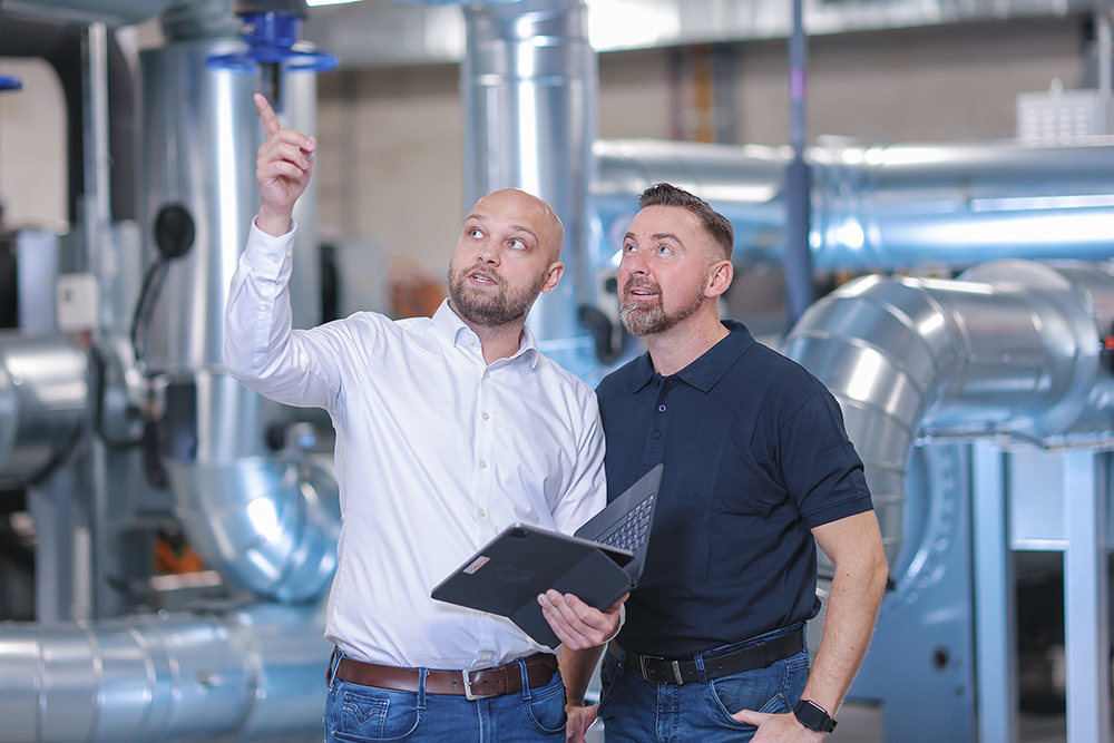 Zwei Mitarbeiter der Firma Heinrich Krumme besprechen etwas vor einer Industrieanlage