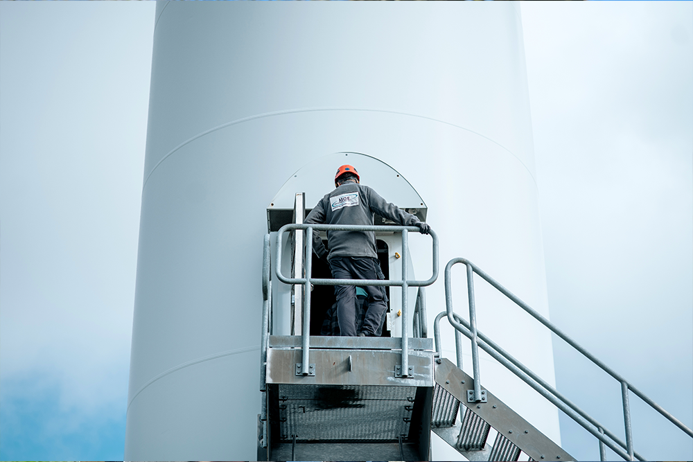 Mitarbeiter der Firma M.O.E. steht an dem Eingang einer Windkraftanlage