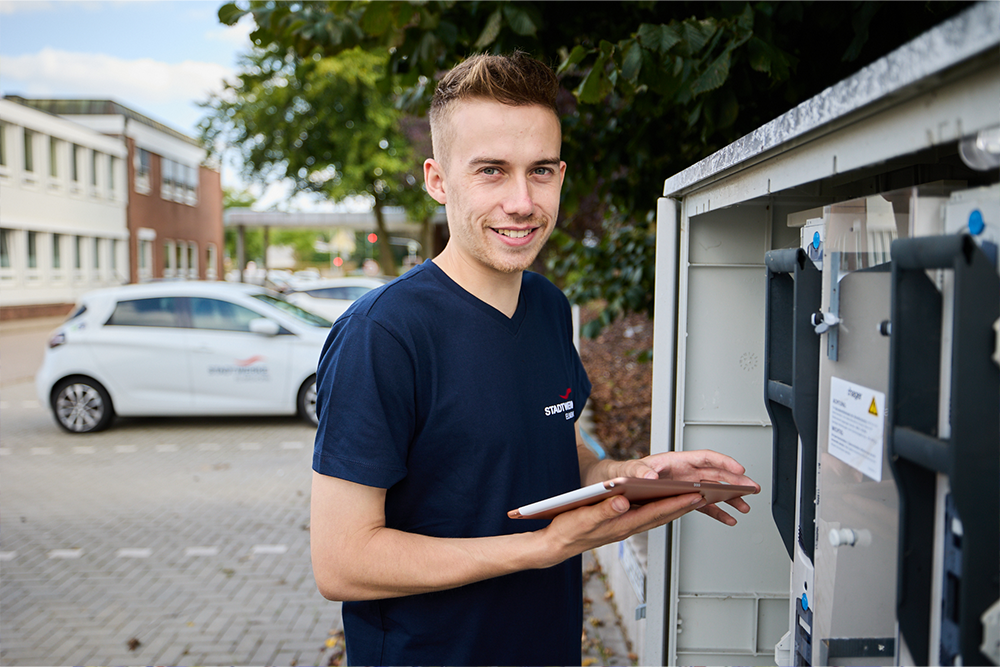 Mitarbeiter der Stadtwerke Elmshorn steht vor einem Stromkasten und liest Daten aus